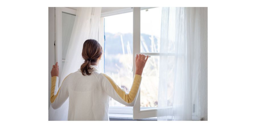 Foto: Frau macht das Fenster ganz auf um Stoßzulüften, eine effektive Methode, um Schimmel vorzubeugen.