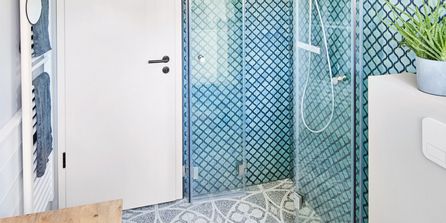 Kleines Gästebad mit Fliesenmuster an Wand und Boden und einer klappbaren Dusche