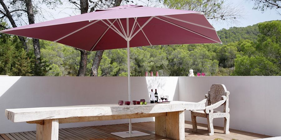 Sonnenschirm von Caravita neben einem Outdoor-Esstisch auf einer Terrasse. - Caravita
