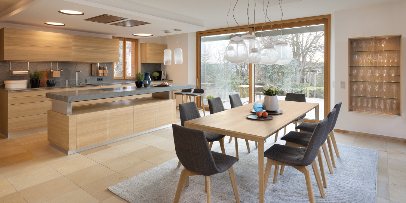 Offene Wohnküche mit Holzfronten und Esstisch.